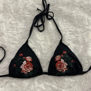 Svart bikiniöverdel  - Säljer denna jättesöta bikini överdel från Lindex, köpt för jättelängesen och används inte längre. Fint broderi av blommor på framsidan och i fint skick.