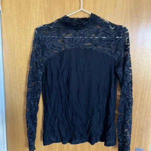 Svart tröja med spets - En fin svart tröja med spets upptil och på armarna. Halvpolo. Ser blå ut i ljuset på bilden. Silket material🖤