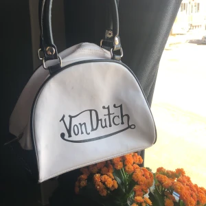 Von dutch väska/ Von dutch mini bowling väska - Hej! Säljer min väska som jag köpte på en secondhand den är en handväska och har några defekter som att den har ett blått streck på baksidan som man kan se. Den har en von dutch tag men står också made in Thailand vet ej om den e fejk, föreslå pris💕