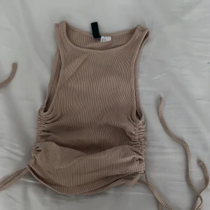 Topp - Säljer denna söta brun/beige toppen som jag inte har någon användning utav längre, den ser rätt så liten ut på bilden men passar galant väl på kroppen. Oerhört skön! 