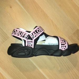 Sprillans nya Buffalo TEC sandaler svart/rosa storken 38 - Helt nya och aldrig använda sandaler från Buffalo, säljer eftersom det är fel storlek. Skulle säga att de är stora 38 (närmare 39). Tjock sula, super coola! 