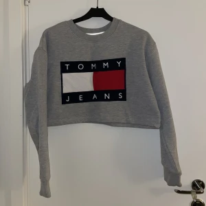 Croppad hilfiger tjocktröja - Croppad Hilfiger-sweatshirt. Jättefint skick. Säljer pga att jag inte använder längre. Perfekt för sommarkvällar.