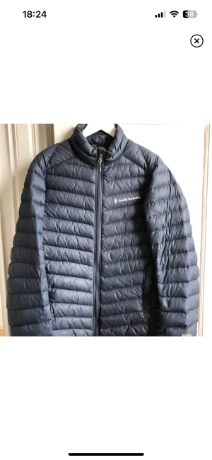 Peak performance dunjacka  - Peak performance dunjacka. Ganska tunn men ändå ganska varm. Storlek S. Mörkblå. Finns ett litet hål mitt på ryggen- se bilden.