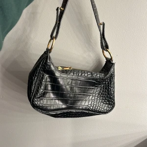 Handväska - Svart handväska från Nelly. Väldigt fint skick, använd några gånger. Säljer då den inte kommer till användning! Hör av dig vid frågor. Kan mötas i Stockholm!