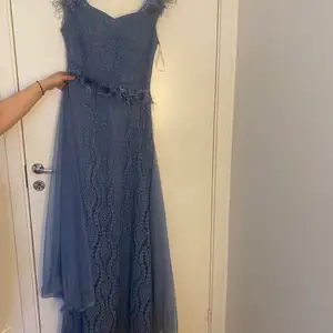 Lång klänning blå med blommor. Den har en lager bakom 