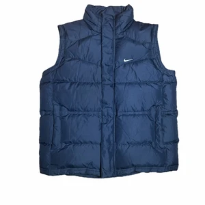 Nike väst - Mörkblå vintage dunväst från Nike. Perfekt till våren!! Älskar den men kommer inte till stor användning. S men lite oversized. Knappt använd så den är i bra skick, har dock en pytteliten vit fläck på ryggen (se sista bilden) Köpare står för frakt 🦦💕 