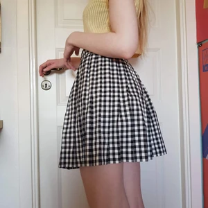 Rutig kjol - Plisserad kjol i svartvitt rutigt tyg, med dragkedja och knapp i sidan.