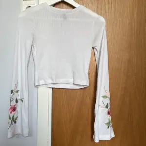Ribbad vit tröja med blommor vid armarna. Från HM i storlek XS. Kan även skicka om önskas, fraktalternativ kan diskuteras.