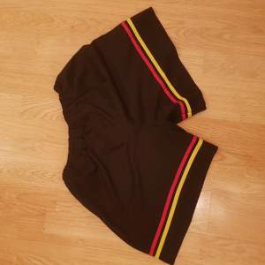 Säljer shorts med ränder av röd & gul.