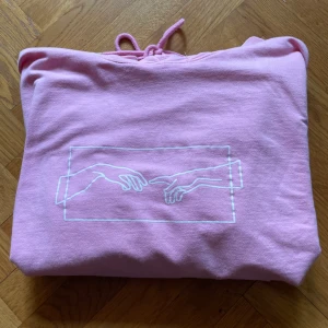 Rosa Hoodie - Rosa hoodie med tryck, rätt tunn i materialet. Det står storlek XXL men skulle säga att den mer är som en L herr. 