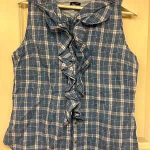 Marc O’Polo-blus - Kortärmad blus från Marc O’Polo i ljusare blå med volanger på framsidan. 