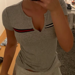 Grå topp Tommy hilfiger - Jag säljer nu min superfina gråa t-shirt topp ifrån Tommy hilfiger!💕den är köpt i usa och är nästan aldrig använd💕kontakta mig vid fler frågor!
