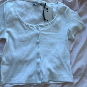 Vit ribbad topp  - En fin basic ribbad topp med knappar. Går att öppna. Aldrig använt med prislapp på. Storlek S men finger även bra för xs eller m. 