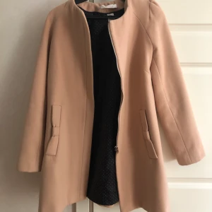 Rosa kappa - Rosa kappa med fin rosett detalj vid fickorna. Storlek 34/36