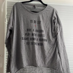 Lössittande tröja som går längre ner på baksidan i storlek XL - Tröja i fina skick med en längre del som täcker rumpan där bak. Är i väldigt tunt material. Har ett tryck med text som inte är slitet öht. Normal i storlek!  Jag har katt och kanin!