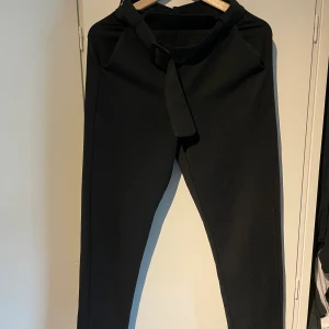 Kostymbyxor  - Supersnygga svarta konstymbyxor från Gina Tricot. Dekorativt skärp i midjan. I nyskick. Strl S. 