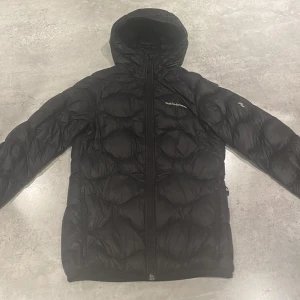 Peak performance Helium dunjacka  - Jättefin Peak Helium säljes billigt. Den här jackan med huva är otroligt lätt och packbar. Ett vind- och vattenavvisande skal tillsammans med högkvalitativ 90/10-dunvaddering gör den perfekt för alla tillfällen.