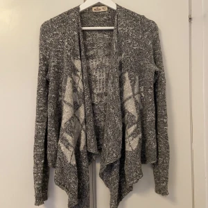 Stickad cardigan från Hollister - Grå stickad tröja med mönster i vitt. Storlek XS/S. Från Hollister. Mjuk och skön att ha på sig, sticks inte. 