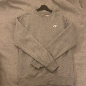 Nike grå sweatshirt - En simpel men snygg grå Nike sweatshirt i storlek S/T (T står för tall, men har ingen större betydelse i storlek)  Den är i ett mycket bra skick utan några defekter. Säljes eftersom den ej kommer till användning. Nypriset är 630kr