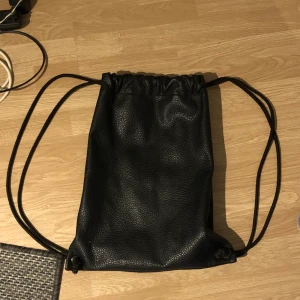 Väska - Svart väska (typ ”gympapåse”) i läder från Lindex. ca 42cm lång och 38cm bred :) 50kr + 66kr frakt !