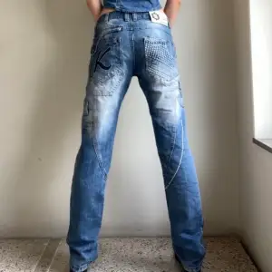 Lågmidjade jeans från C-IN-C med snygga detaljer. Det står kosmoalien på framsidan. Innerbenslängd: 81 cm. Midjemått: 86 cm.