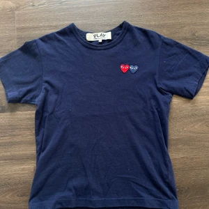 Play marinblå t-shirt - Marinblå T-shirt från play Comme des Garcons. Köpt i London. Kvitto finns. Nyskick  Nypris är 1000kr