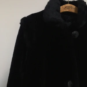 SVART/MÖRKBRUN 1990s FUSKPÄLSKAPPA 🤎 - Svart/mörkbrun längre 1990s kappa i fuskpäls med stora dekorativa knappar. Perfekt till hösten! Svårt att få en bra bild på jackan i höstmörkret men den är superfin. Märkt som storlek 36 men uppskattningsvis storlek M. 200 kr plus porto. 🤎