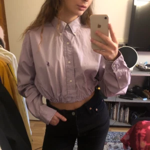 Croppad Polo Ralph Lauren skjorta - Grålila croppad Ralph Lauren skjorta med resår i midjan, inköpt i en vintage shop i London. Står ingen storlek men skulle säga att den sitter som en S ✨ Kan mötas upp i Göteborg annars står köparen för frakten 