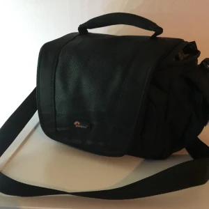 Kameraväska - Filmbolaget rensar! Denna gång är det en kameraväska som söker ny ägare. Väskan passar de flesta kamerahus med mindre objektiv. Mått kan skickas. 