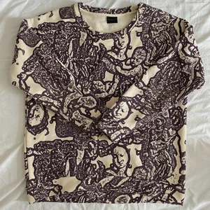 Tröja - Krämvit tjocktröja med mörklila mönster. Strl M. Nyskick