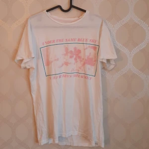 Vit t-shirt - Vit t-shirt från pull & bear med snyggt tryck. Text: under the same blue sky. Sitter som S. Frakt tillkommer. OBS: rabatt ges vid köp av flera plagg
