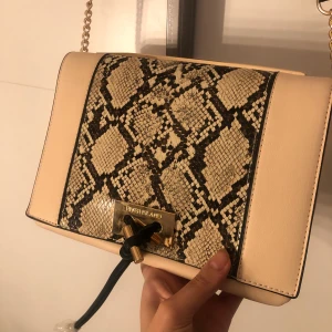 Beige väska från river island - En beige ormmönstrad väska från river island. Aldrig använd. Alltså helt ny och fräsch.