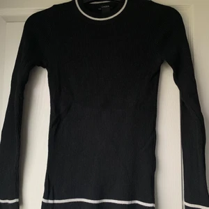 Ribbad långärmad  - En svart ribbad långärmad med vita ränder längst ner på ärmarna och i kragen! Sitter väldigt fint på. 