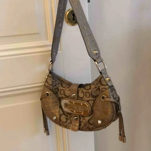  - Superfin beige/guldig väska från Guess. Väskan är vintage och gjord av ett tyg men gulddetaljer⭐️