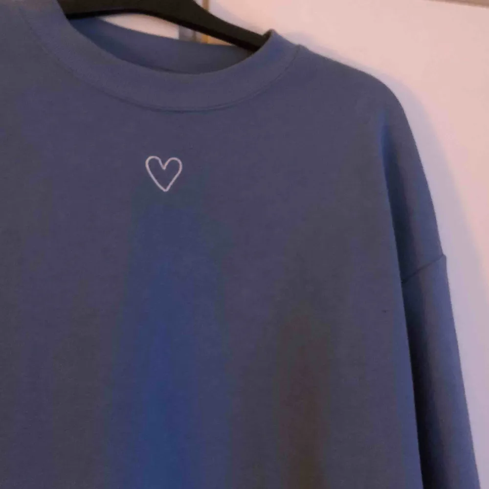 Jättefin blå ”Loose” sweatshirt med ett gulligt hjärta på, köpt för inte så längesen på Monki. Säljer pga att den inte används, frakten är inräknad i priset :) . Hoodies.