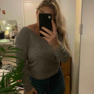  - En grå tröja med refflat material. Tröjan har en v-ringning som man kan justera som man vill. Tröjan är extremt stretchigt. 