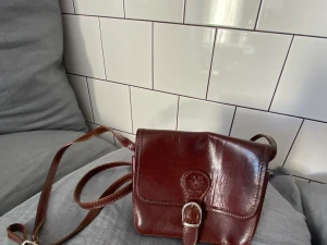 Läderväska från Italien - Liten väska tillverkad i läder, perfekt storlek för en liten väska. Väskans mått; ungefär 17x14cm. (Kan mötas upp i Stockholm - även posta men köparen står för frakten). 