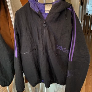 Jacka från Adidas - En svart/lila jacka från Adidas. Jag har köpt den second hand men den var lite för stor, så jag har aldrig använt den. 