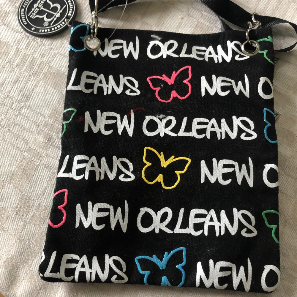 Svart väska med ”New Orleans” på. Oanvänd och har lapp kvar. Ca 15 x 10 cm. . Väskor.