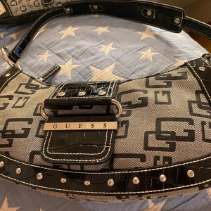 Guess hand väska 50% ner  - En svart tyg och lack väska av märket Guess