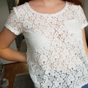 Spets tröja  - Vit/genomskinlig spets t-shirt med en ficka på framsidan.