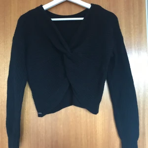 Svart kabelstickad med kors (öppen rygg) - Jätte söt och snygg tröja från hollister som passar både sommar och vinter. Svart skön stickad tröja med vändning vilket ger en öppen rygg! Tröjan är i fint skick och passar en xs 