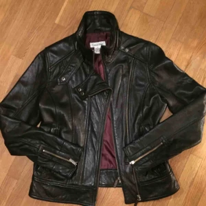  - Supersnygg jacka i mjuk lammnappa av Calvin Klein.  Fint skick, har ett litet jack på h. ärmen (sista bilden) Svart, kort modell, 2 fickor med dragkedja, storlek M men passar 36/38. Finns i Helsingborg