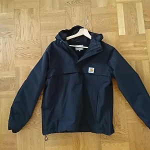 Carharrtt Anorak svart - Carharrtt Anorak med fleece-foder. Stl M. Utmärkt skick. Originalpris 1600. Har blivit liggandes och förtjänar ett bättre hem :)