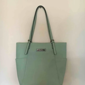  - Calvin Klein-väska i snygg mintgrön! Har tyvärr spillt lite kaffe i ena hörnet (sista bilden) men är i övrigt i gott skick! Kan skickas mot frakt eller mötas upp i Uppsala. 
