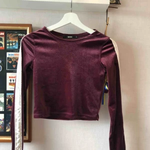  - Långärmad magtröja av sammet, lilaröd. Med en vit sammet rand på ärmarna. Använd fåtal gånger ä. Bra skick