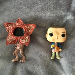 stranger things funko pop - Två coola stranger things funko pop dockor från första säsongen, en av Eleven och en Demodog. Jättegulliga och nostalgiska! har tyvärr inte lådorna kvar, så de shippas som de är. 70 kr styck, 130 för båda🧇❤️
