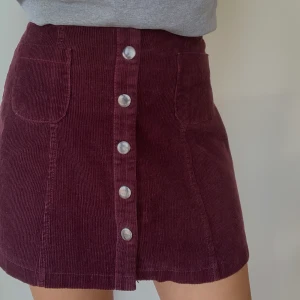 Manchesterkjol - Manchesterkjol i vinrödfärg. Köpt secondhand och därför en aning urtvättat i färgen, annars i fint skick. Observera att den är insydd därbak, lätt att sprätta upp om så önskas. ☀️ Köparen betalar frakten. 63kr☀️