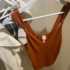 Linne - Croppat v ringat linne i ribbat klart kopparfärgat / mörkare orange tyg med breda axelband med knutar på