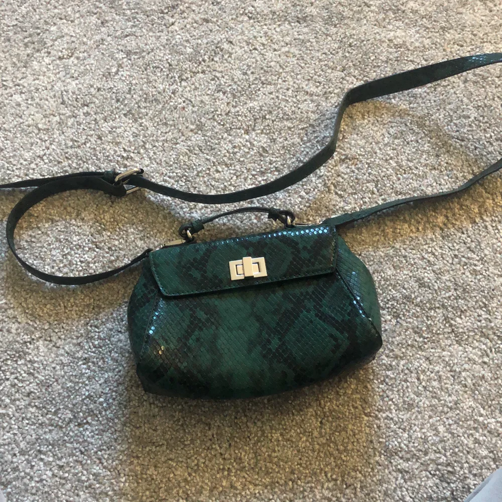 Säljer min gröna väska från ginatricot, väskan är i bra skick och är bara använd några gånger. Väskan har ett kort handtag och ett längre band. Silver spenen. . Accessoarer.